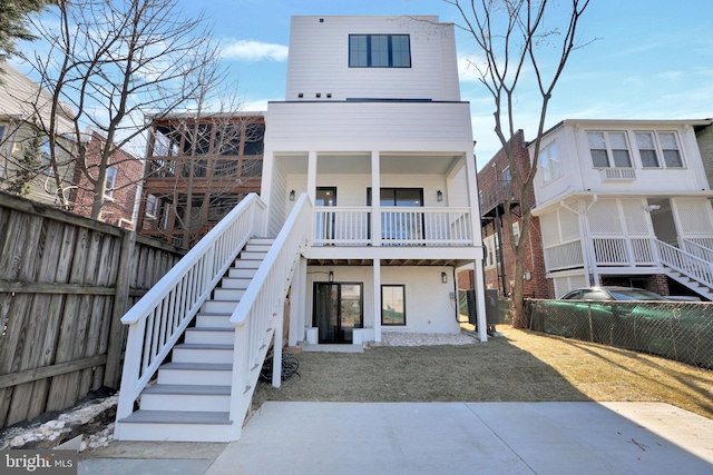 rear view of property featuring stairs and fence