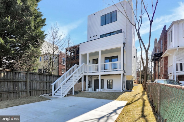 rear view of house featuring cooling unit, a yard, a fenced backyard, and stairway