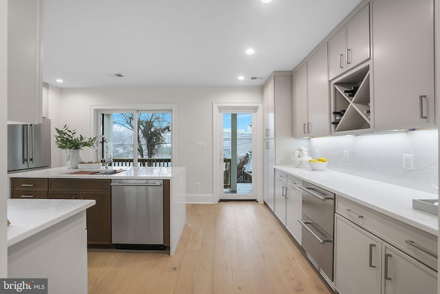 kitchen with recessed lighting, light wood-style flooring, stainless steel dishwasher, a warming drawer, and a sink