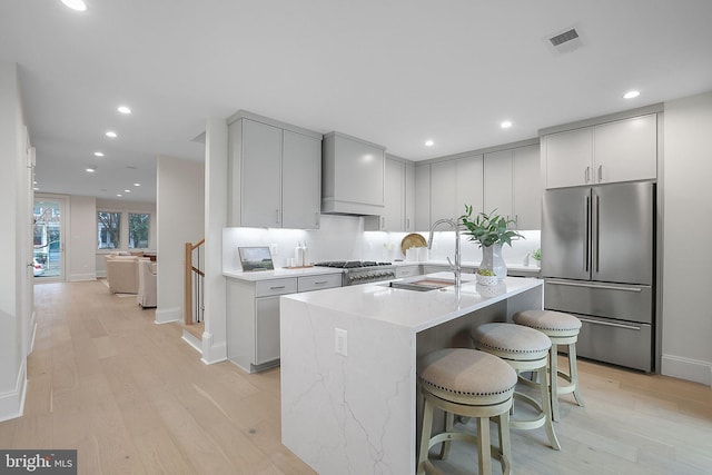 kitchen with visible vents, light wood-style flooring, freestanding refrigerator, a sink, and a kitchen breakfast bar