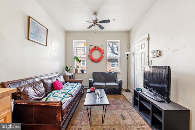 living area featuring baseboard heating and a ceiling fan