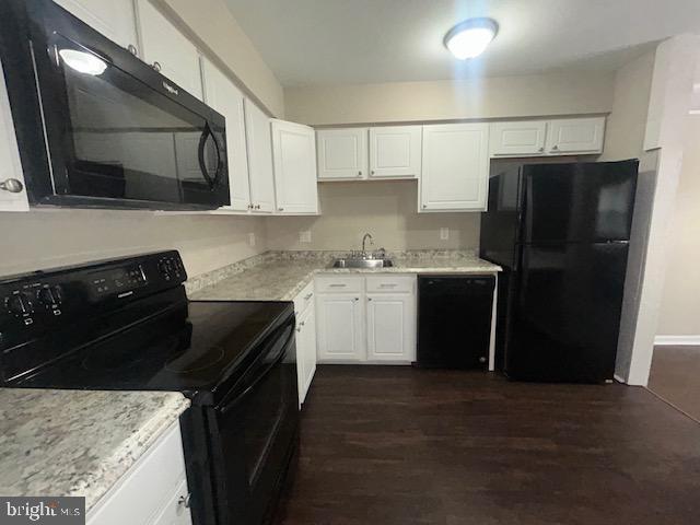 kitchen featuring dark wood-type flooring, white cabinets, a sink, and black appliances