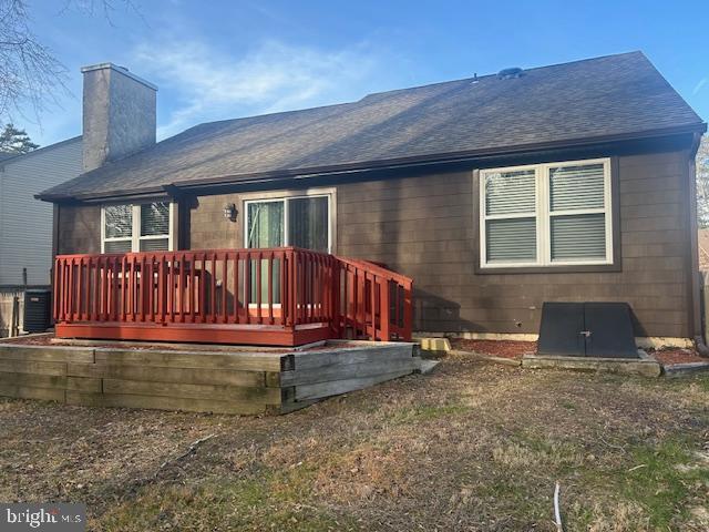 rear view of property featuring roof with shingles, a chimney, and cooling unit