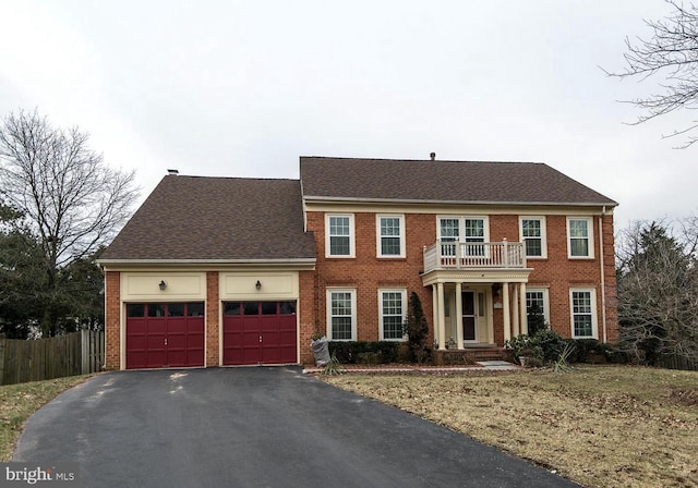 view of front of home with a garage, brick siding, a balcony, and aphalt driveway