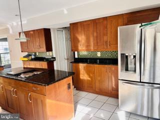 kitchen featuring decorative backsplash, dark countertops, brown cabinets, stainless steel appliances, and light tile patterned flooring