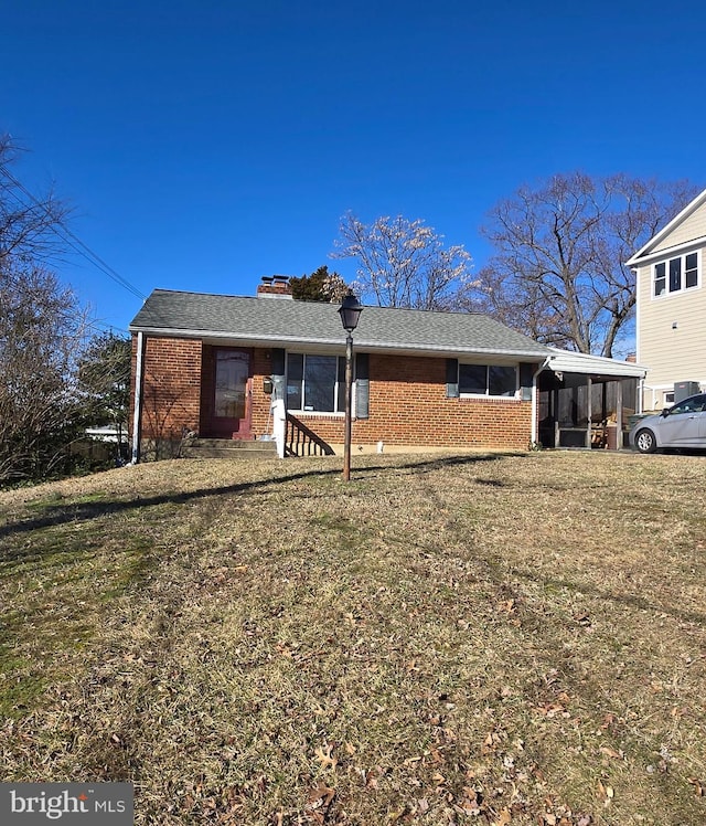 view of front of property featuring a chimney, a front lawn, and brick siding