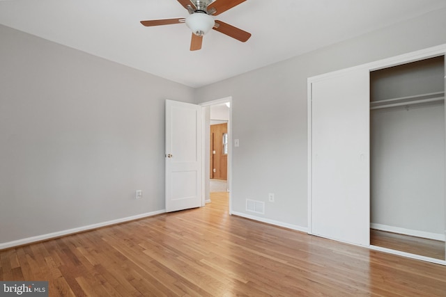 unfurnished bedroom with a closet, visible vents, baseboards, and wood finished floors