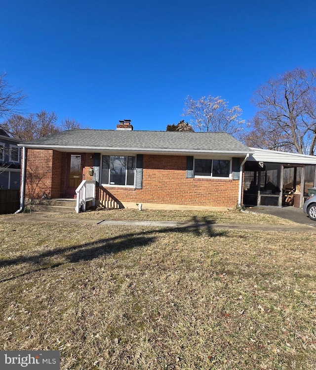 view of front facade with a carport, a front yard, brick siding, and roof with shingles