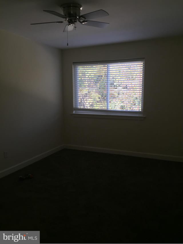 unfurnished room featuring ceiling fan and baseboards