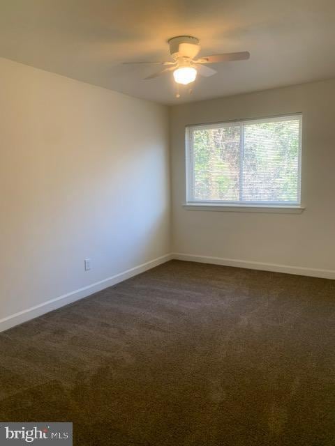 empty room with dark carpet, baseboards, and ceiling fan