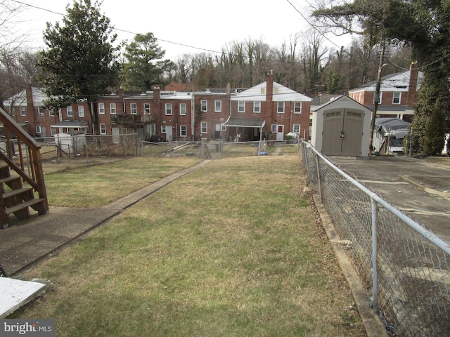 view of yard with a shed, an outdoor structure, fence, and a residential view