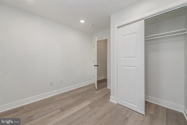 unfurnished bedroom featuring recessed lighting, a closet, baseboards, and wood finished floors