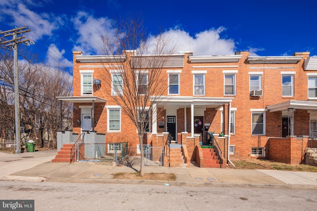 view of property featuring a fenced front yard, cooling unit, covered porch, brick siding, and a gate