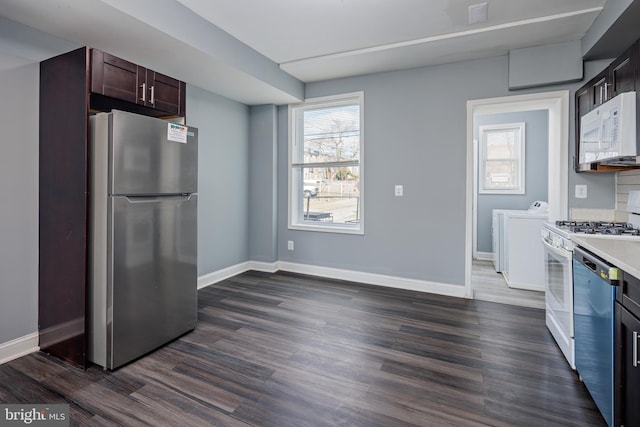 kitchen with appliances with stainless steel finishes, a healthy amount of sunlight, dark wood-type flooring, and washing machine and clothes dryer