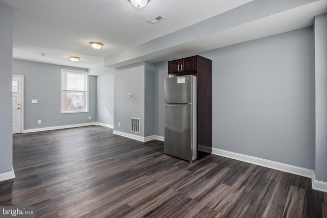 spare room with dark wood-style flooring, visible vents, and baseboards