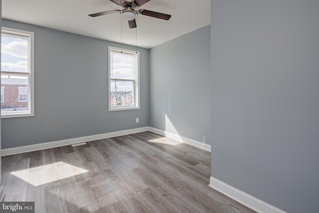 spare room featuring a ceiling fan, baseboards, and wood finished floors