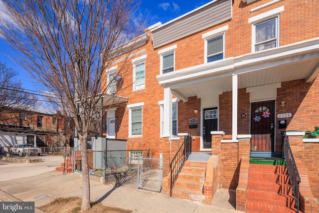 townhome / multi-family property with a porch, a gate, and brick siding