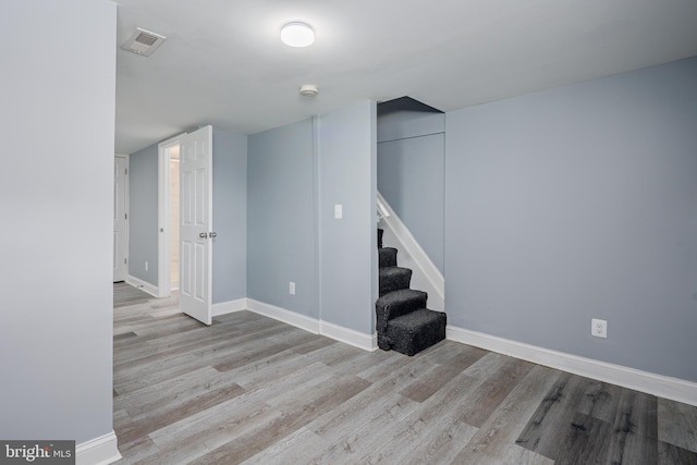 finished basement featuring visible vents, stairway, baseboards, and wood finished floors