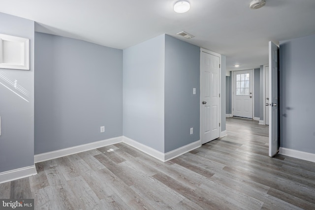 empty room featuring wood finished floors, visible vents, and baseboards