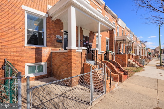 exterior space featuring a gate, a residential view, fence, and brick siding