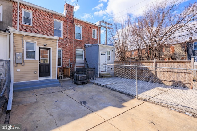 back of house with entry steps, brick siding, a chimney, and fence