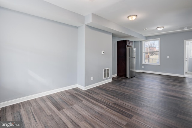 unfurnished room featuring baseboards, visible vents, and dark wood-style flooring