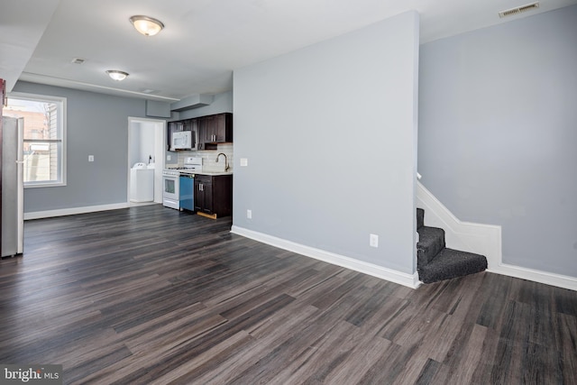 unfurnished living room with stairs, dark wood-type flooring, visible vents, and baseboards