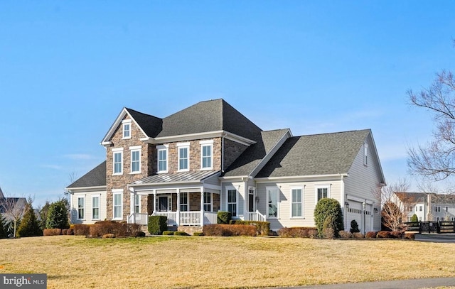 view of front facade featuring an attached garage, stone siding, covered porch, and a front yard