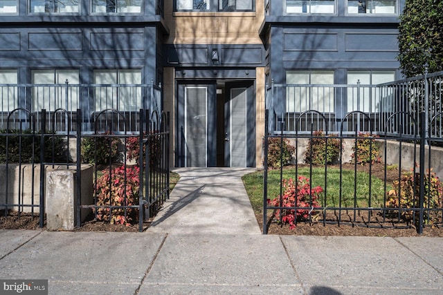 entrance to property with a gate, stone siding, and fence