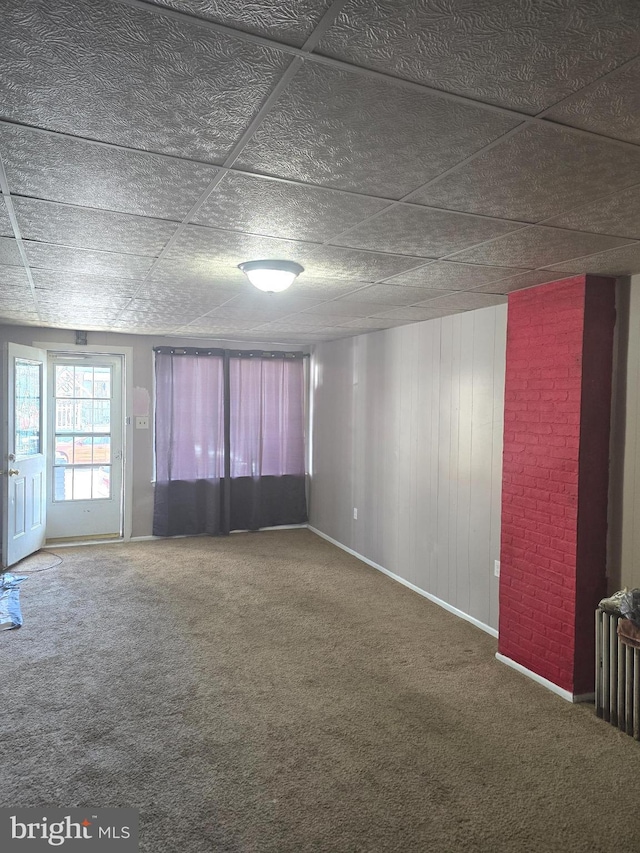 carpeted empty room featuring baseboards and wood walls