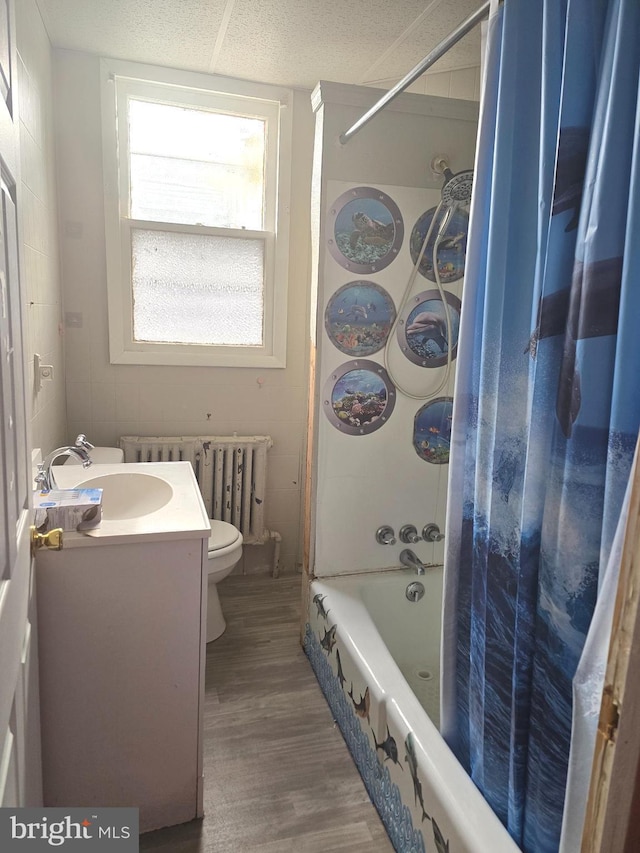 full bathroom featuring radiator, toilet, shower / tub combo with curtain, wood finished floors, and vanity