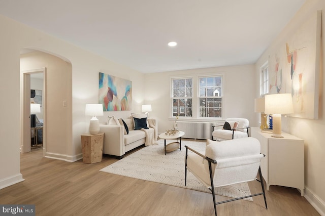 living room with arched walkways, recessed lighting, radiator, wood finished floors, and baseboards