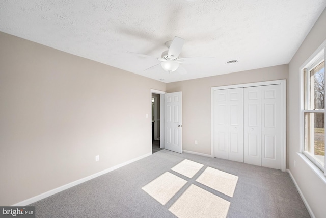 unfurnished bedroom with a closet, light carpet, a textured ceiling, and baseboards