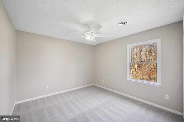 carpeted spare room with a ceiling fan, baseboards, visible vents, and a textured ceiling