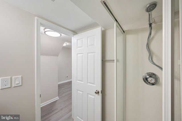 interior space with a shower, wood finished floors, and baseboards