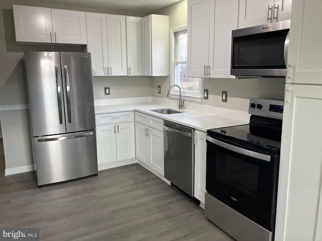 kitchen with light countertops, appliances with stainless steel finishes, a sink, and white cabinets