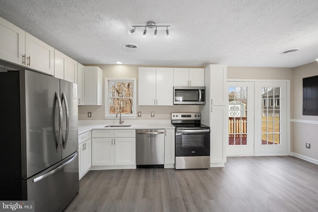 kitchen featuring appliances with stainless steel finishes, a sink, visible vents, and white cabinetry