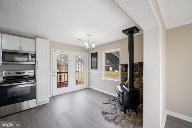 interior space featuring a textured ceiling, dark wood-type flooring, a wood stove, and baseboards