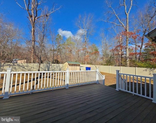 deck with an outbuilding, a shed, and a fenced backyard