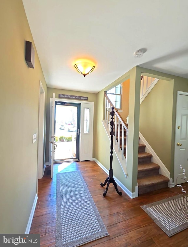 entrance foyer with a wealth of natural light, wood-type flooring, baseboards, and stairs