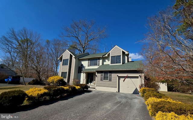 traditional-style home featuring an attached garage and aphalt driveway