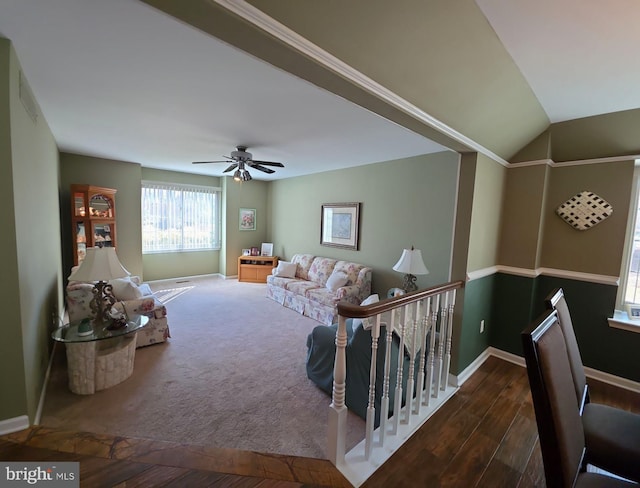 living room featuring carpet floors, ceiling fan, vaulted ceiling, wood finished floors, and baseboards