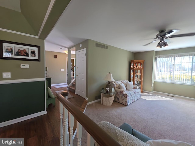 living area with visible vents, ceiling fan, baseboards, and stairs