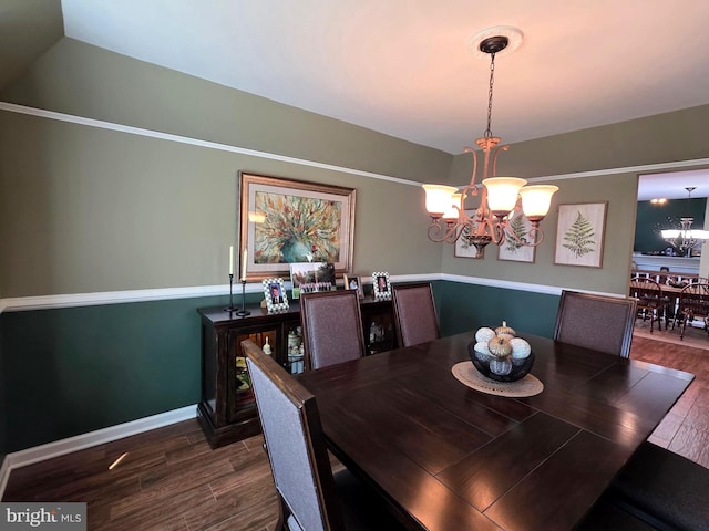 dining area featuring dark wood-type flooring, baseboards, vaulted ceiling, and a notable chandelier