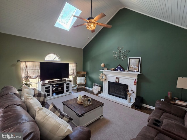 living room featuring a skylight, a fireplace, ceiling fan, high vaulted ceiling, and baseboards