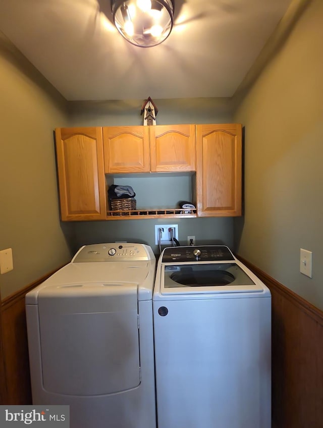 washroom with wainscoting, washing machine and dryer, and cabinet space