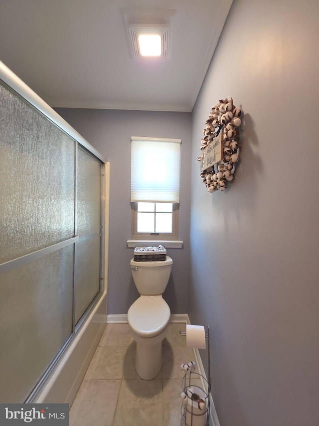 bathroom featuring enclosed tub / shower combo, baseboards, toilet, and tile patterned floors