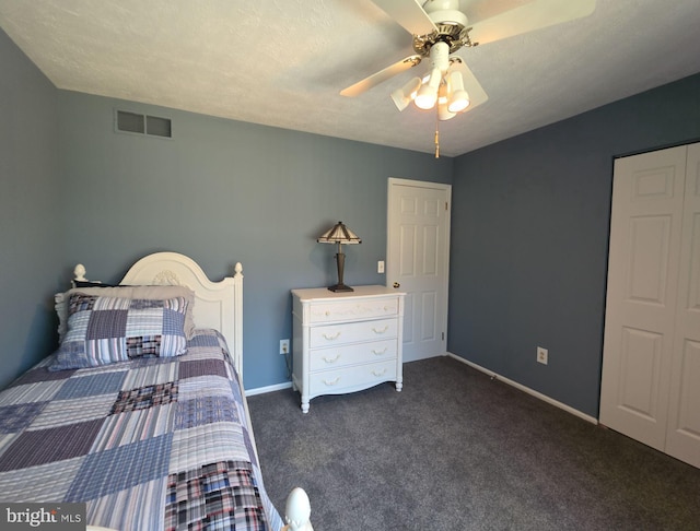 bedroom with ceiling fan, a textured ceiling, visible vents, baseboards, and dark colored carpet