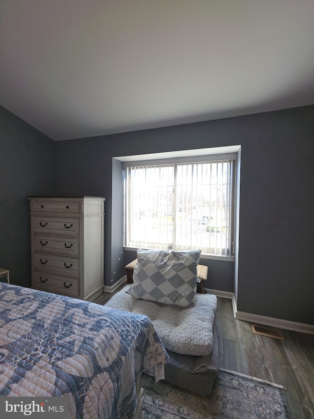 bedroom with multiple windows, baseboards, and wood finished floors