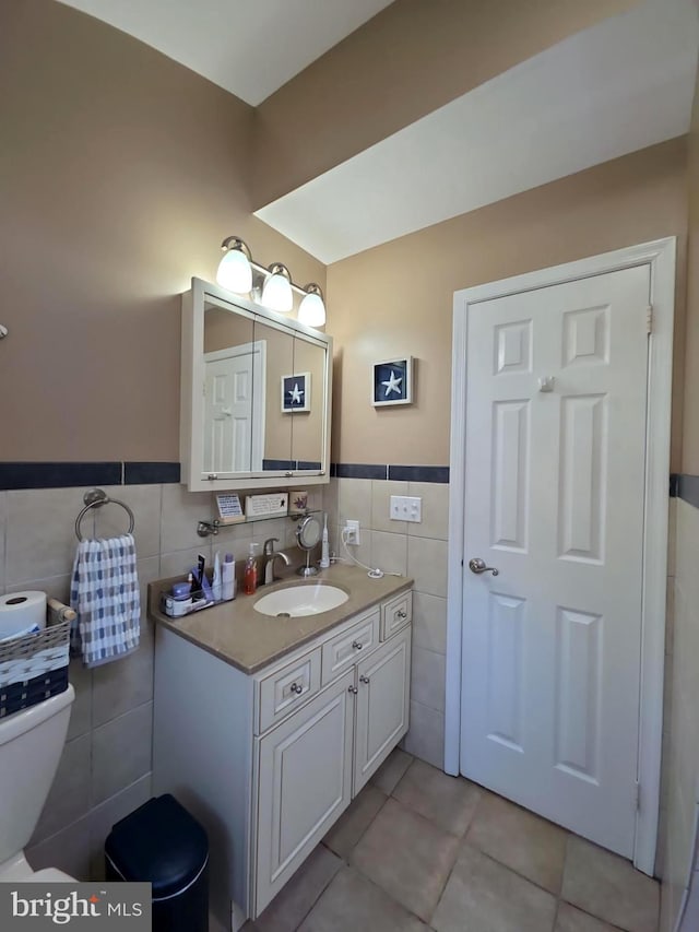 bathroom featuring tile walls, toilet, wainscoting, vanity, and tile patterned floors